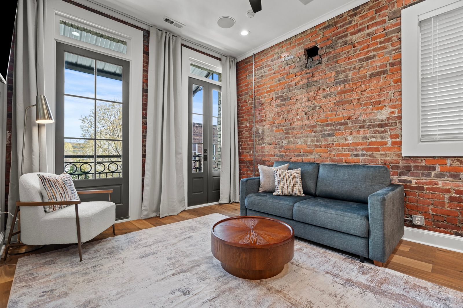 Aurelia Suite living room with exposed brick and French doors to the balcony